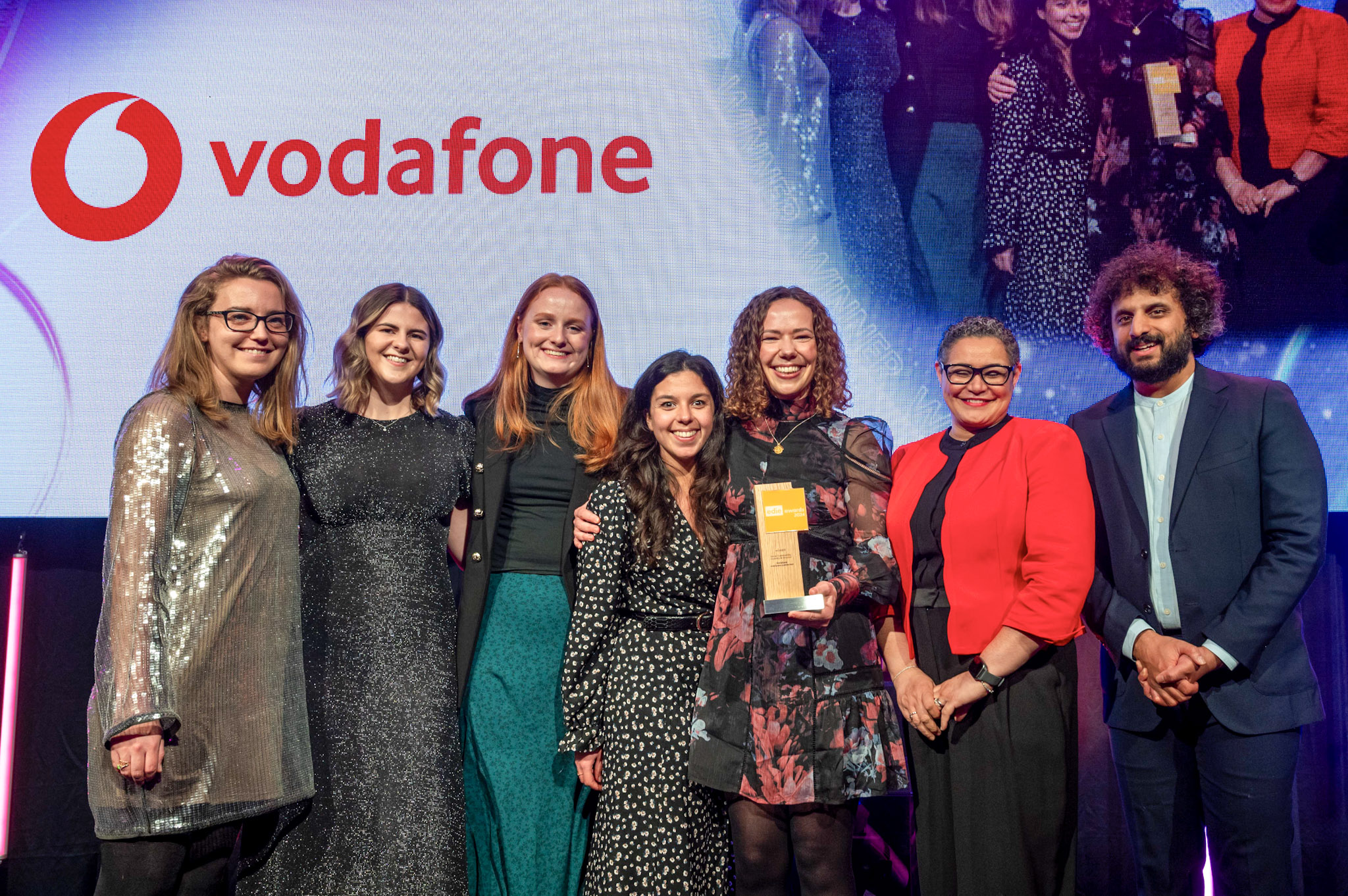 image of Vodafone employees collecting an awards trophy from comedian Nish Kumar onstage at the edie Awards