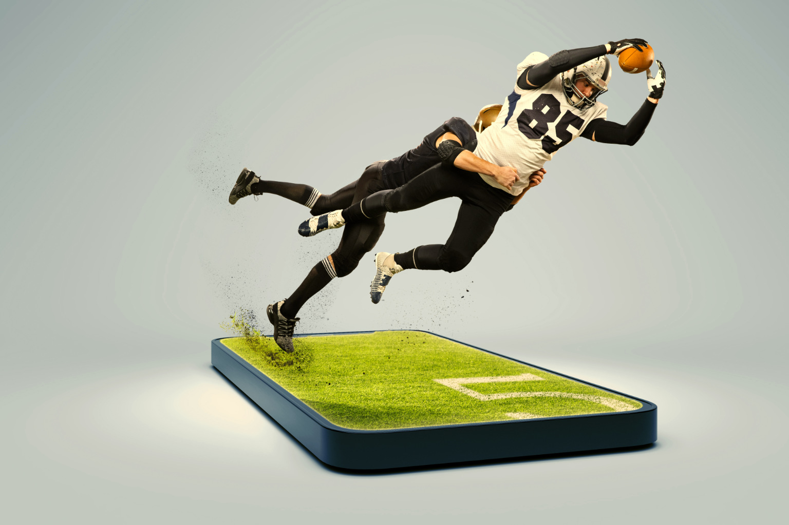 stock image collage of two American football players emerging out of a smartphone laid flat on a blank surface